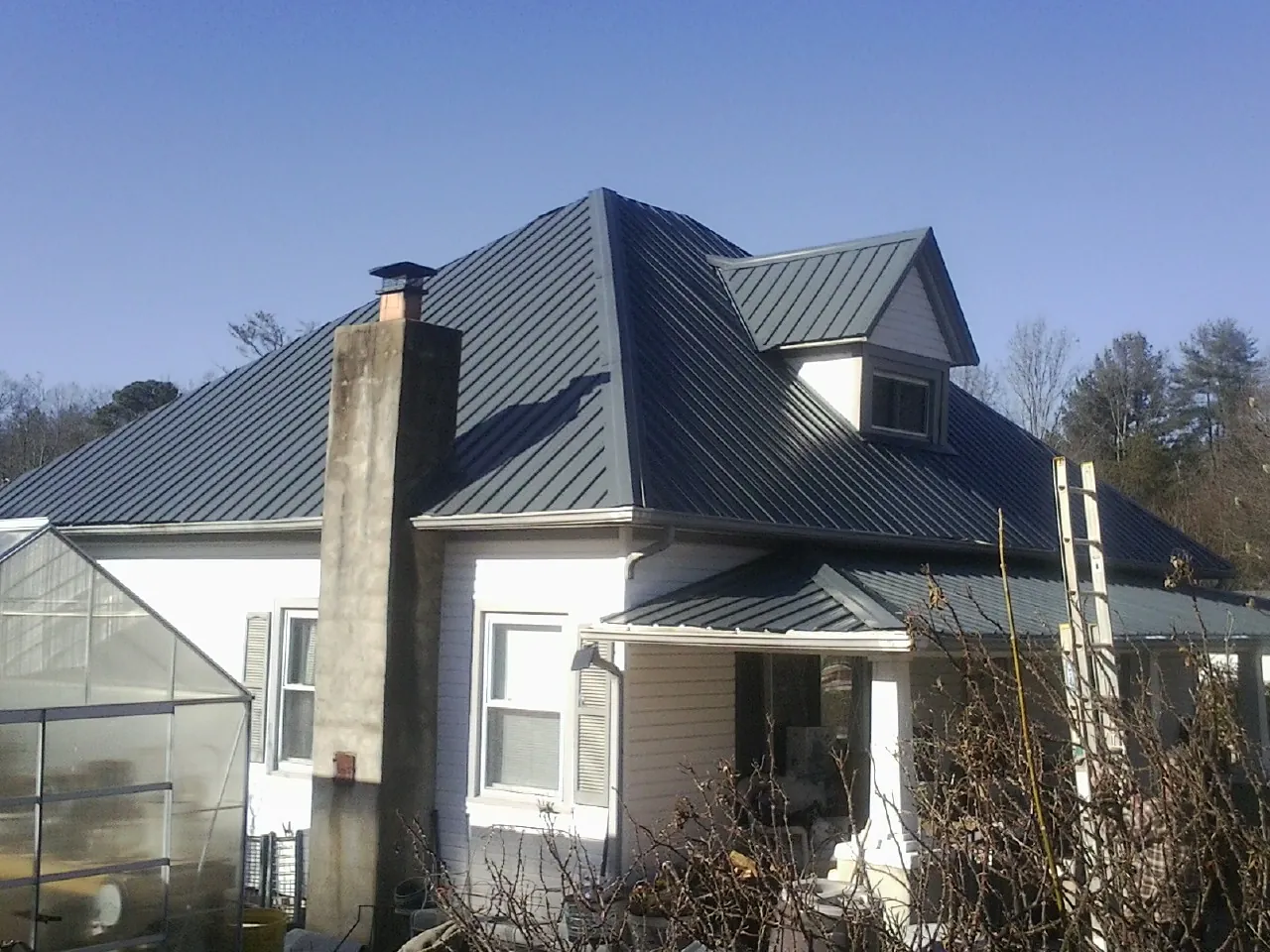 Dark blue standing seam metal roof on a white farmhouse with dormer — Slate & Tile Roof Repair by Roofing Brothers in Enoree