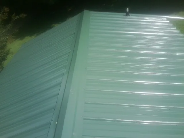 New green metal panels meeting at the ridge of a roof — Flat Roof Repair work by our crew in Enoree