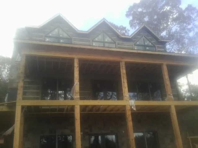 Dormers and porch framing on a large log home under construction — Roof Coating work by our crew in Enoree