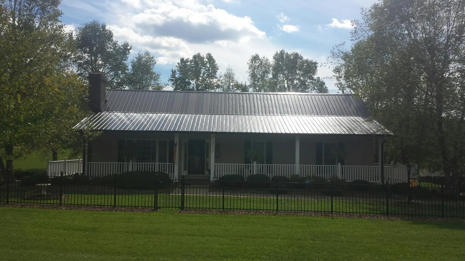 Gray metal roof on a brick ranch with a full width front porch — Gutter Guard Installation work by our crew in Enoree