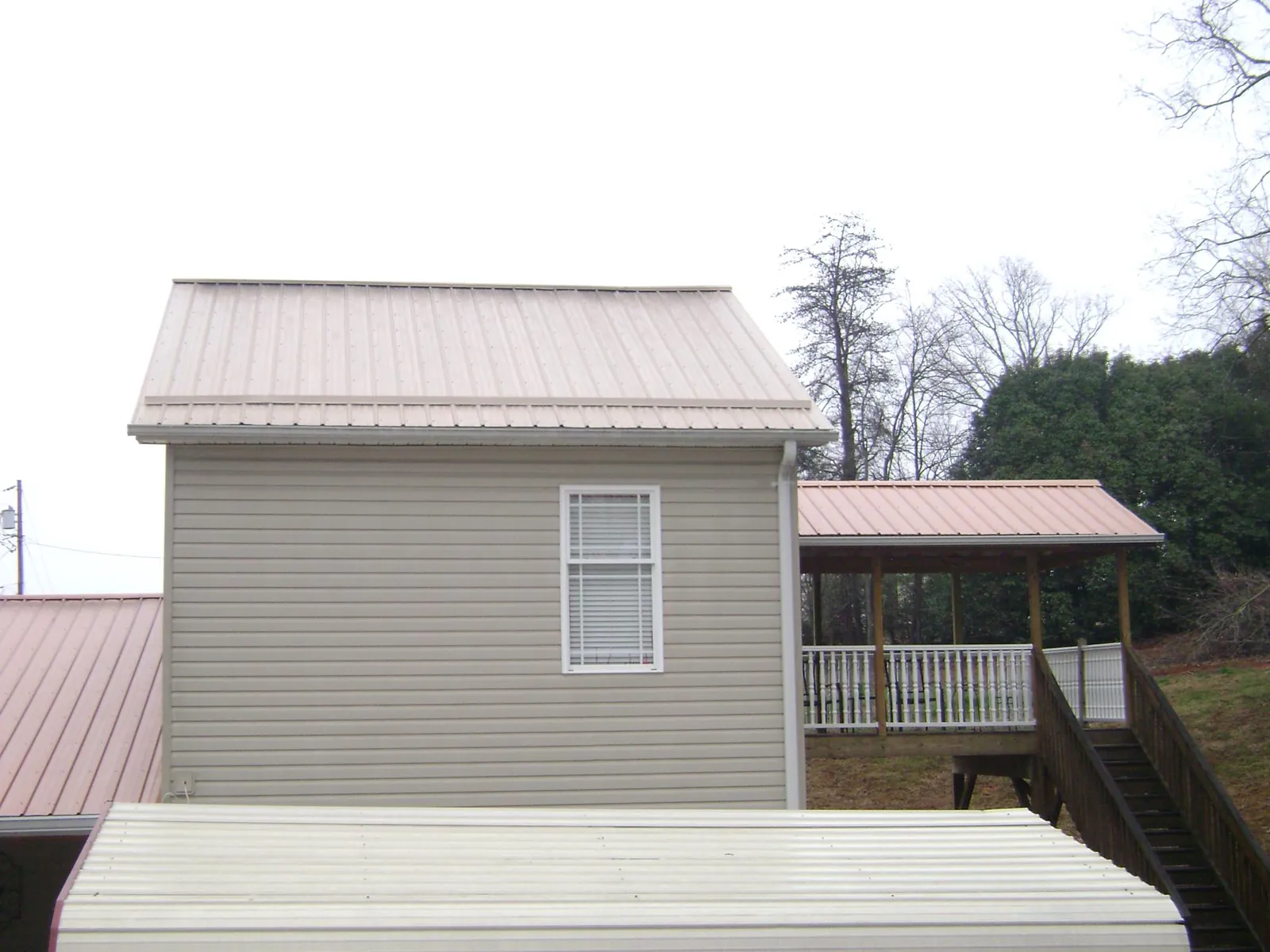 Tan metal roofs on a two story addition and attached porch, from a Roof Replacement job in Enoree