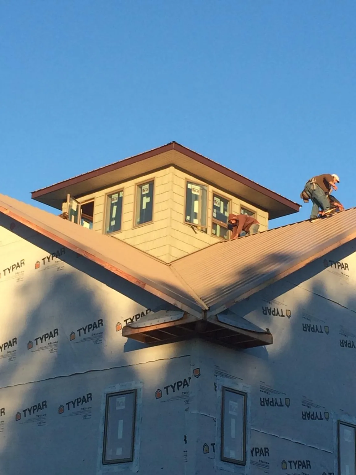 Roofers working around a rooftop cupola on a new metal roof at sunset — Roof Waterproofing in Enoree by Roofing Brothers